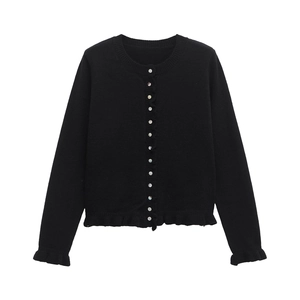 Detail of black knit cardigan featuring pearlescent buttons and ruffled hem edges