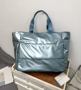 Close-up of metallic light blue quilted travel tote with side zippers on wooden surface
