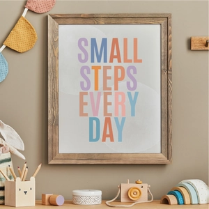 Close-up of a wooden frame with 'SMALL STEPS EVERY DAY' text in a cozy home setting