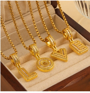 Detail of four gold-colored initial necklaces forming LOVE with zircon-inlaid pendants