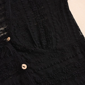 Detailed view of black lace fabric texture and brown circular buttons on the long sleeve top