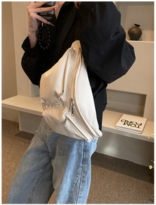 Detail of creamy white crossbody bag showing multi-layered zippers and soft faux leather texture