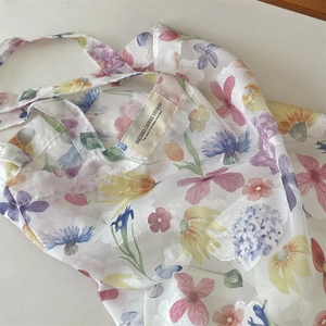 Close-up of translucent mesh tote bag featuring colorful floral prints and brand label