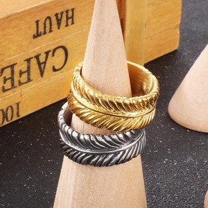 Detailed view of punk style leaf texture rings on a wooden stand in gold and silver
