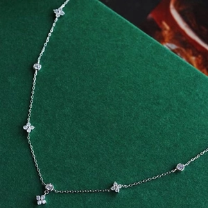 Collar de plata con trébol de cuatro hojas y circonitas sobre fondo verde