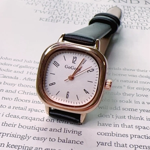 Close-up of a vintage square quartz watch with black leather strap and rose gold metal case