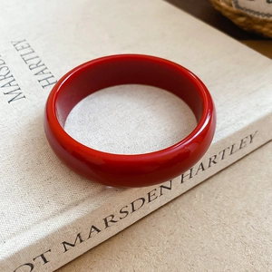 Artistic close-up of vibrant red resin round bangle resting on a vintage book