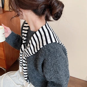 Close-up of a striped knit shawl draped over a dark gray sweater for an elegant winter look
