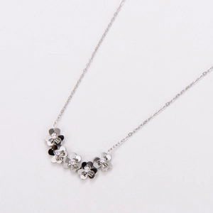 Macro detail of silver necklace featuring five clover charms with sparkling center stones