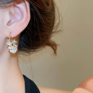 Close-up of 18k gold plated earrings featuring translucent white crystal petals on a model