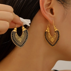 Detail of vintage bohemian hollow-out gold earrings with black bead trim on model