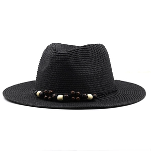 Détail d'un chapeau fedora noir tressé avec des perles en bois marron et crème
