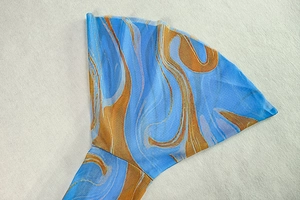 Détail des poignets évasés et de l'imprimé marbré bleu et orange sur la robe