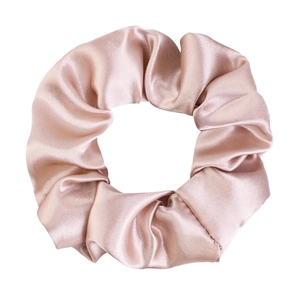 Detailed view of champagne satin scrunchie with soft silk texture and elegant pleats