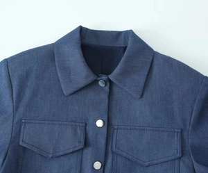 Detail view of denim jacket collar and silver metal buttons on dark blue denim fabric