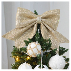 Close-up of golden glitter Christmas bow topper ornament on a festive green pine tree