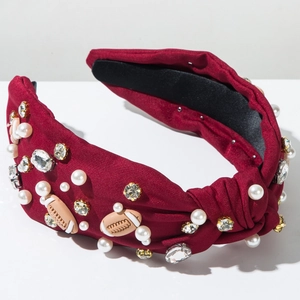 Close-up of knotted burgundy headband with rhinestones, pearls and football ornaments