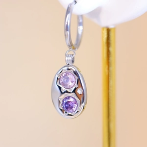 Silver stainless steel oval earrings with two purple starburst gems on gold stand