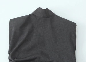 Dettaglio macro della spallina imbottita grigio scuro e trama twill di questo blazer