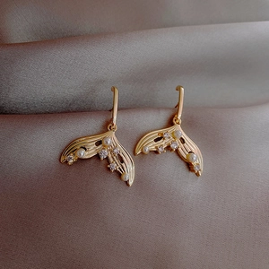 Detailed view of gold fishtail earrings featuring white pearls and sparkling zircons