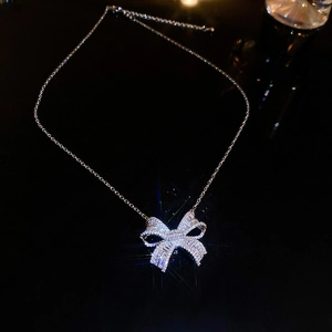 Close-up of silver bow pendant with sparkling cubic zirconia on a fine link chain