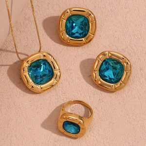 Close-up of vintage jewelry set with square blue zircon and 18K gold-plated texture