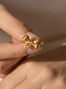 Detailed close-up of a 18K gold-plated bow ring with intricate ribbon textures