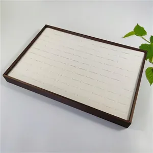 Detail view of the 100-slot rectangular wooden jewelry display tray with white velvet lining