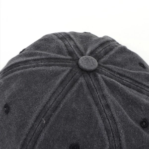Macro shot of corduroy fabric texture and six-panel stitching on dark grey baseball cap