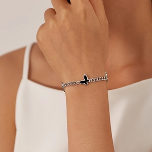 Elegant stainless steel chain bracelet with a black butterfly charm on a woman's wrist