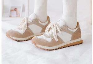 Close-up of beige suede sneakers on white fabric with model wearing cotton socks