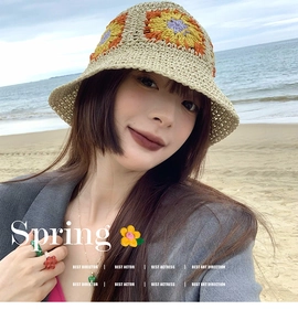 Detail of hand-crocheted beige bucket hat with colorful floral patterns on a sunny beach