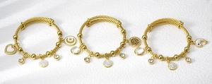 Detailed close-up of golden stainless steel wire bracelets with heart and tree charms