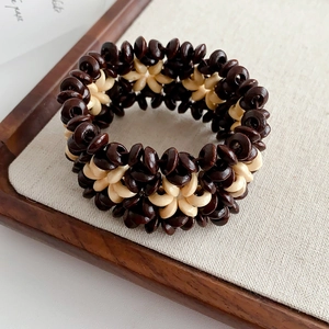 Detailed view of dual-color coconut shell wood beads on a bohemian elastic bracelet