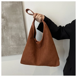 Detail view of brown suede tote bag featuring a spacious trapezoidal design and shoulder strap