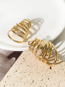 Detailed macro view of gold multi-layer spiral hoop earrings on a decorative stone