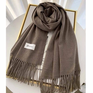 Close-up of thick coffee brown cashmere scarf with classic fringe and brand label