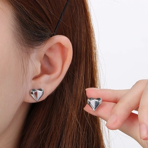 Close-up of heart-shaped silver earrings showing the size and delicate polished metal finish