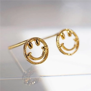 Close-up of gold-plated hollow smiley face stud earrings with a polished metallic finish