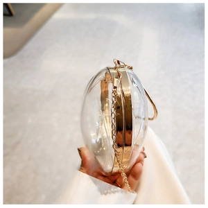 Detail of transparent egg-shaped acrylic clutch bag with gold frame and chain strap