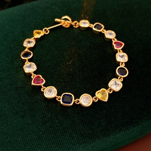 Détail d'un bracelet vintage doré avec zircons colorés en forme de cœur et fermoir OT