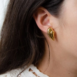 18k gold plated heart drop earring with sculptural metallic finish on a model