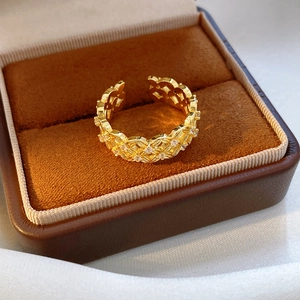 Detailed macro view of 18k gold-plated open ring with hollow flower patterns and cubic zirconia