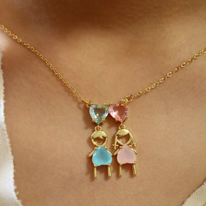 Gros plan d'un collier avec pendentifs garçon et fille ornés de zircons cœur rose et bleu