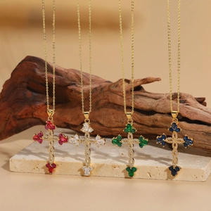 Detail of four colorful cross pendants with zircons and gold chains on a stone stand