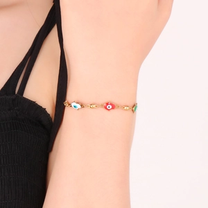 Close-up of golden evil eye bracelet with colorful enamel charms on model wrist