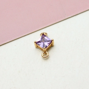 Macro shot of gold plated rhombus charm with square purple zircon for jewelry DIY