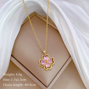 Macro shot of gold clover necklace with pink heart gems on silk, 40+5cm chain length