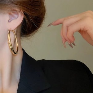 Side view of large chunky gold hoop earrings worn by a model in a black suit
