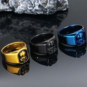 Punk skull rings for men in gold, black, and blue finish on a textured rock background